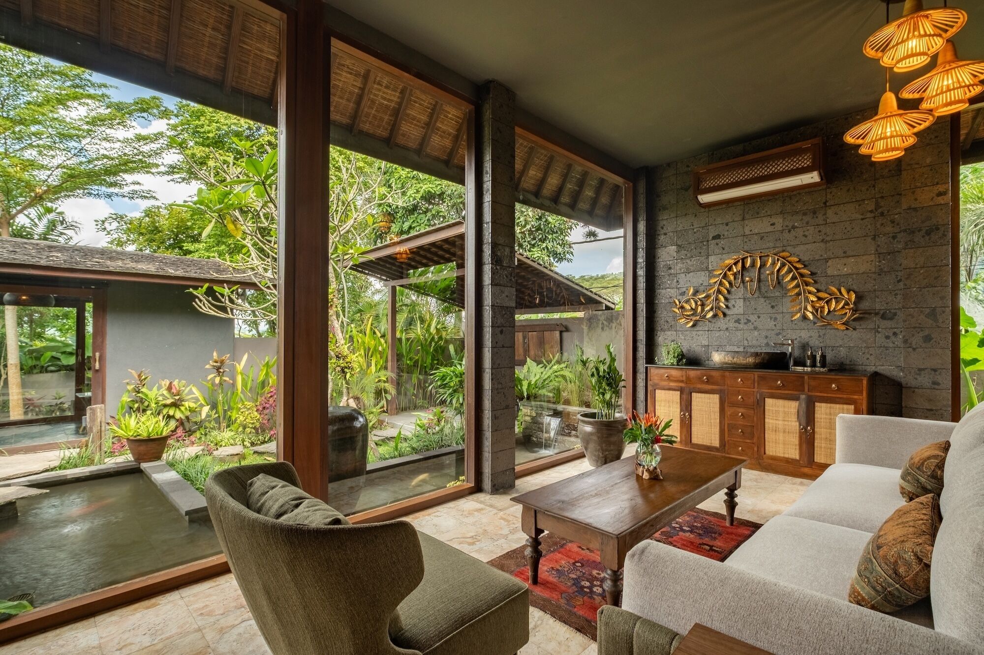 A spacious living area with large windows, a stone fireplace, and a view of a lush garden.