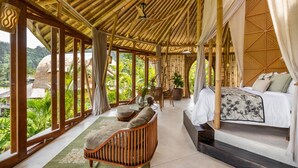 A spacious room with a large bed, a wooden sofa, and a dining area.