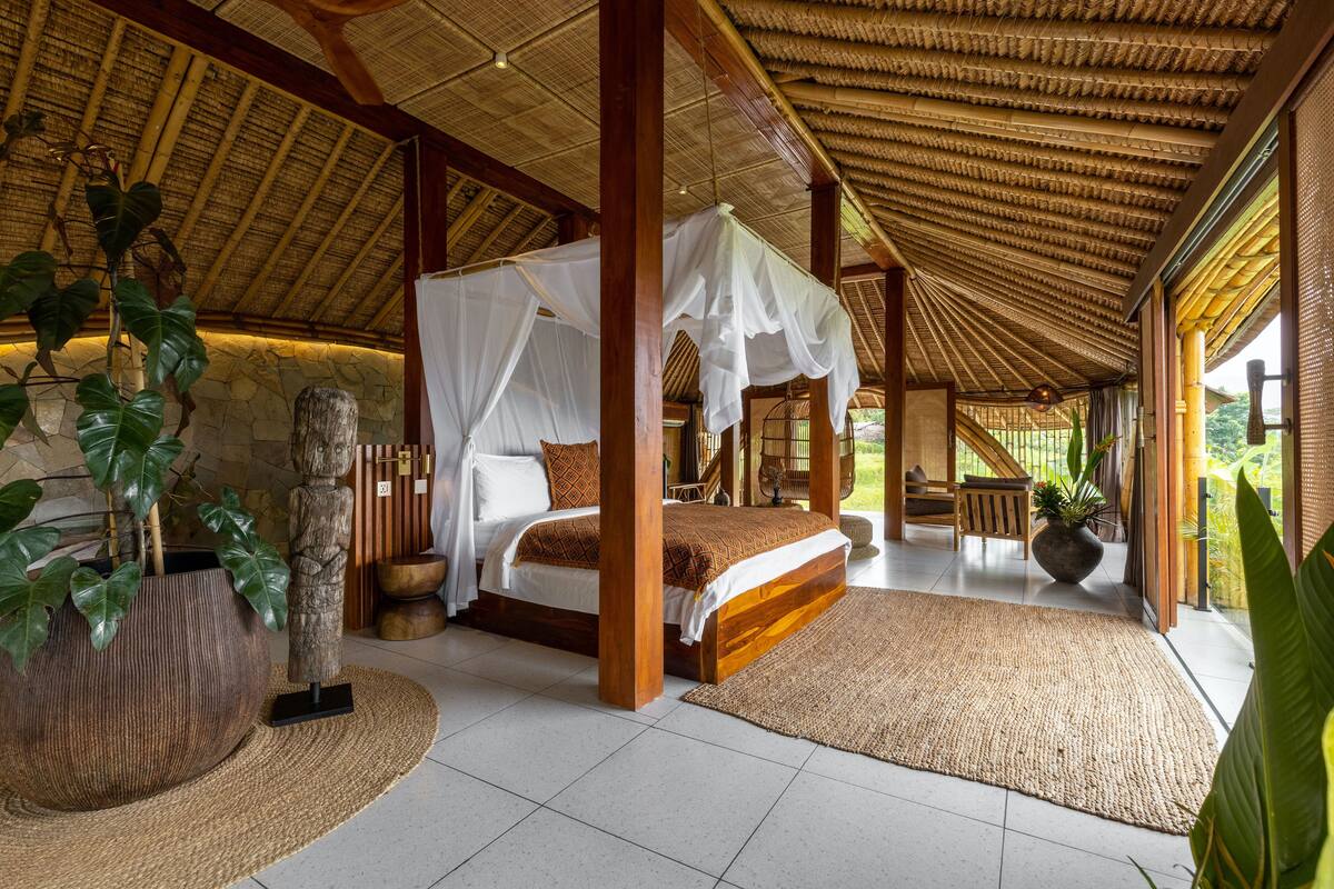 A spacious bedroom with a large bed, a canopy, and a view of the outdoors.