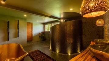 Un espace spa moderne doté d’une grande colonne à la texture particulière, d’un banc en bois et d’un tapis à motifs.