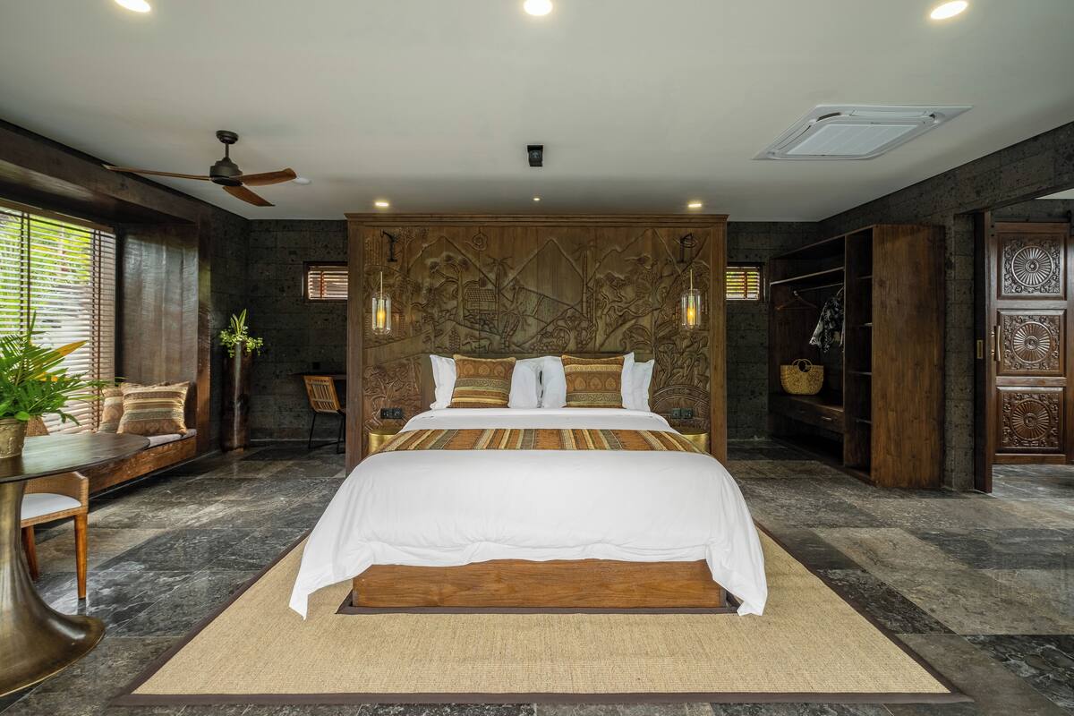 A bedroom with a large bed, a ceiling fan, and a wooden headboard.