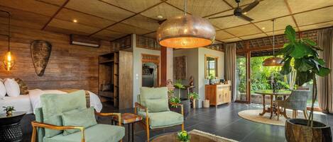 A spacious living area with a high ceiling, a ceiling fan, a large hanging light fixture, and a view of the outdoors.