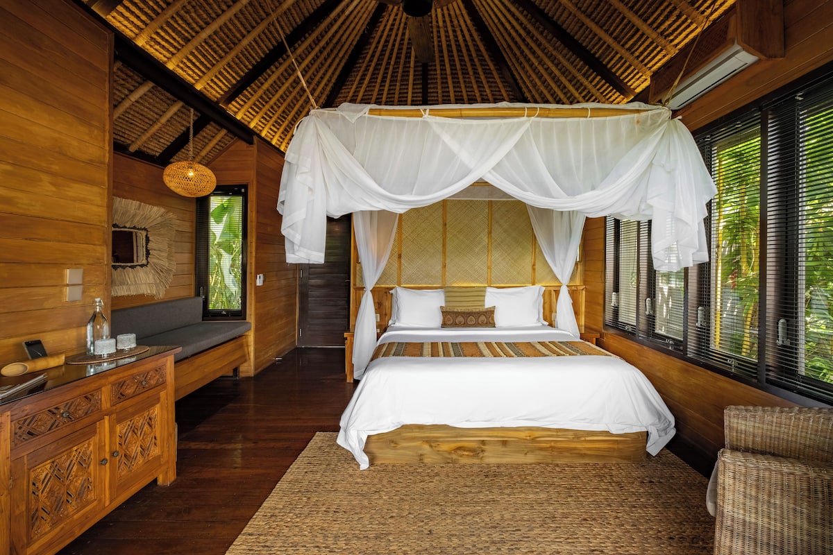 A wooden room with a bed, a bench, and a small table.