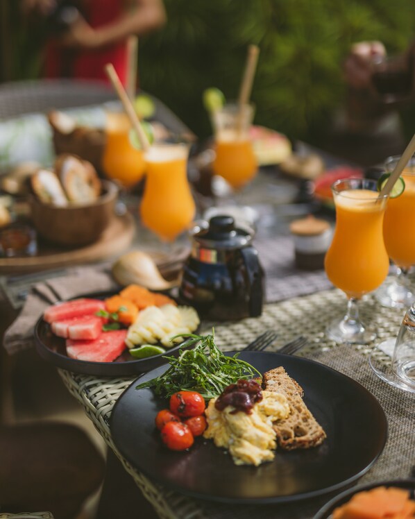 Un desayuno con platos de comida, vasos de zumo de naranja y una cafetera.