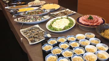 Una mesa de buffet con diversos platos, incluyendo ensaladas, mariscos y otros alimentos ya preparados.
