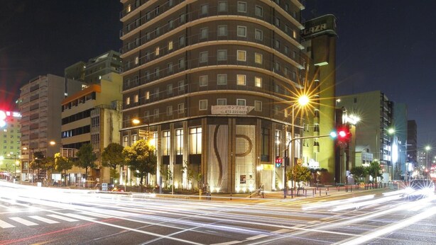 Um hotel com vários andares e fachada curva, com letreiros iluminados e entrada destacada.
