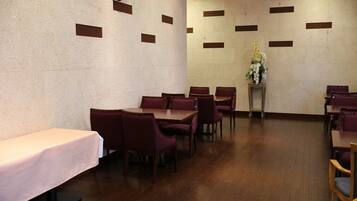 A dining area with tables and chairs, a decorative wall, and a small table with flowers.