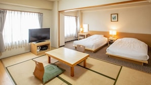 Une chambre d’hôtel équipée d’une télévision, de deux lits, d’une table et d’un canapé.