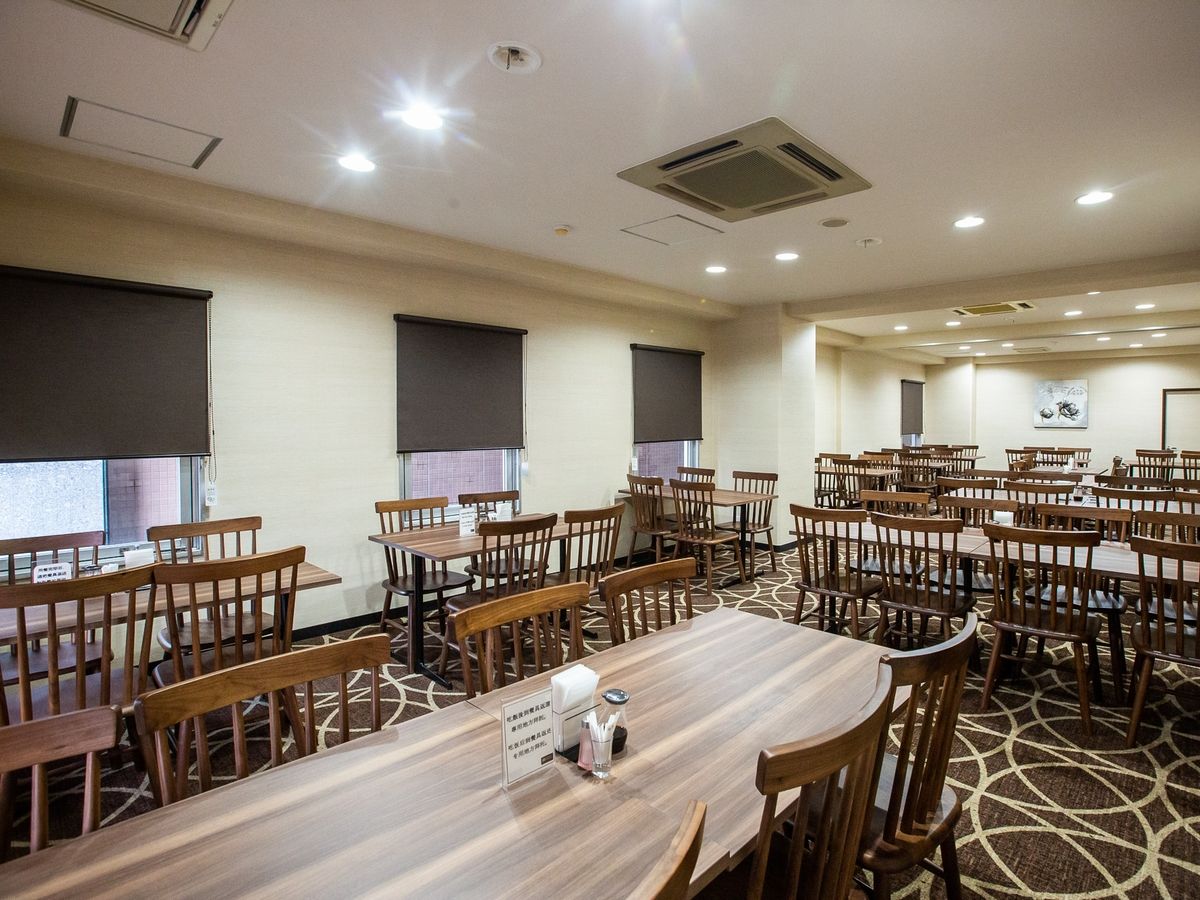 A conference room with multiple tables and chairs, arranged in rows.