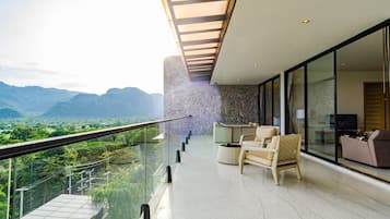 A modern balcony with a glass railing overlooking a mountainous landscape.