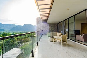 Un balcón moderno con barandilla de vidrio que da a un paisaje montañoso.