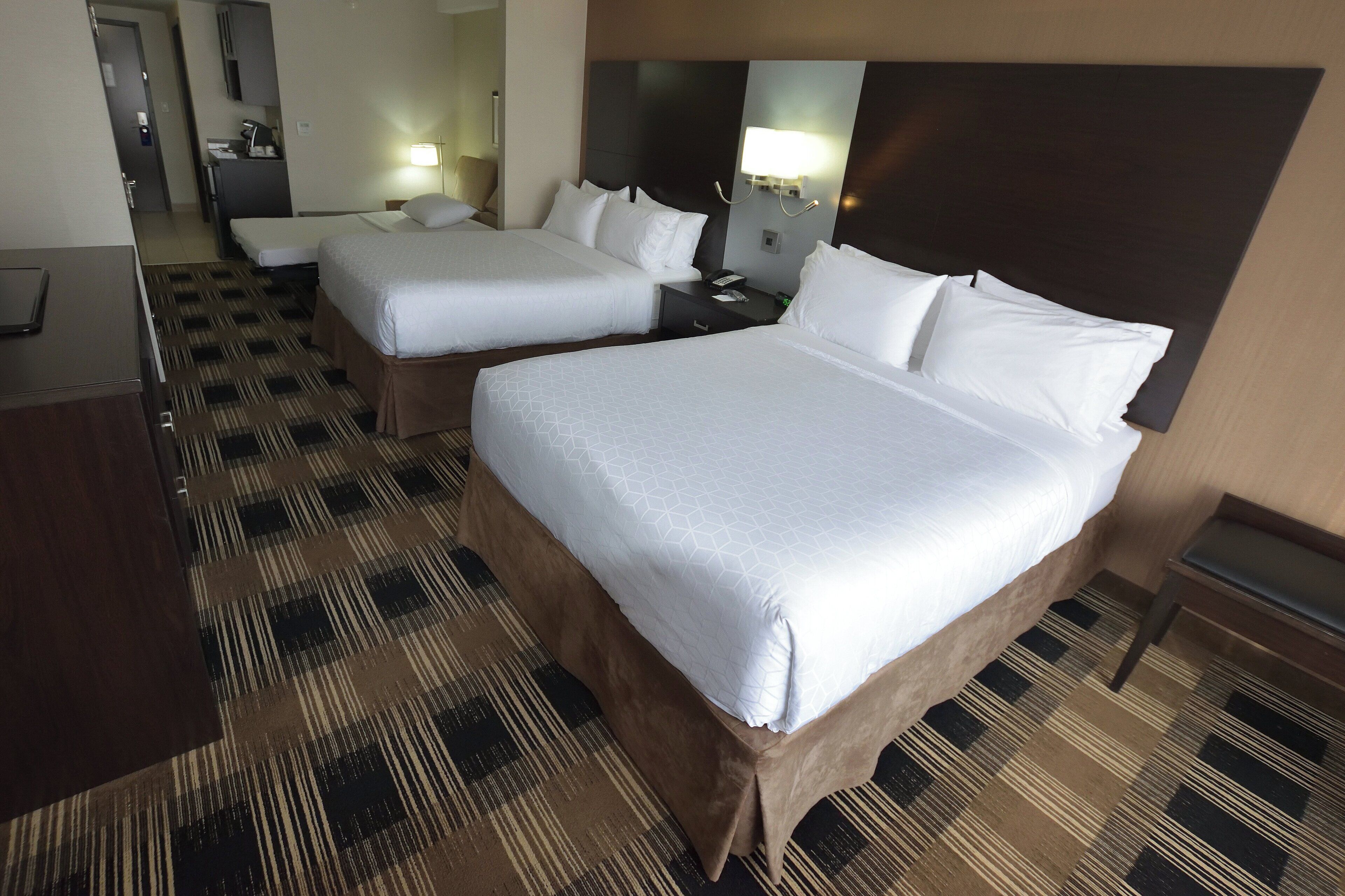 Ein Hotelzimmer mit zwei Betten, einem Schreibtisch, einem Stuhl und Teppichboden.