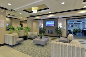 A hotel lobby with seating areas, a television screen, and a reception desk. - Holiday Inn Express & Suites Ottawa East - Orleans by IHG (Ottawa)