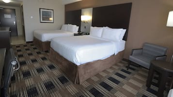 Habitación de hotel con dos camas, un escritorio, una silla y una alfombra estampada.