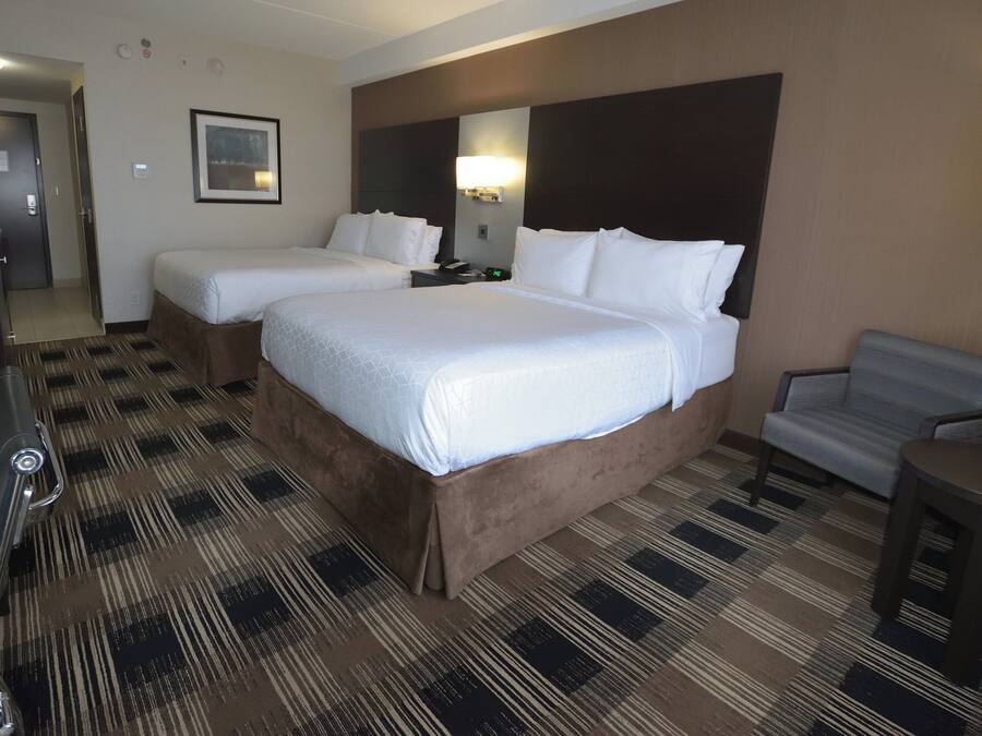 Habitación de hotel con dos camas, un escritorio, una silla y una alfombra estampada.