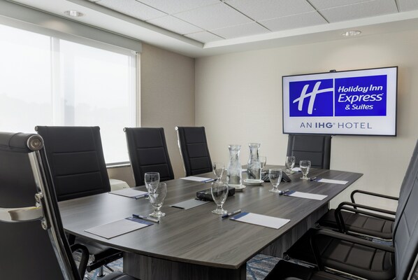 A conference room with a large table, black chairs, and a screen displaying the Holiday Inn Express logo.