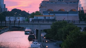 A waterfront with boats docked, a bridge, and a castle-like building in the background.