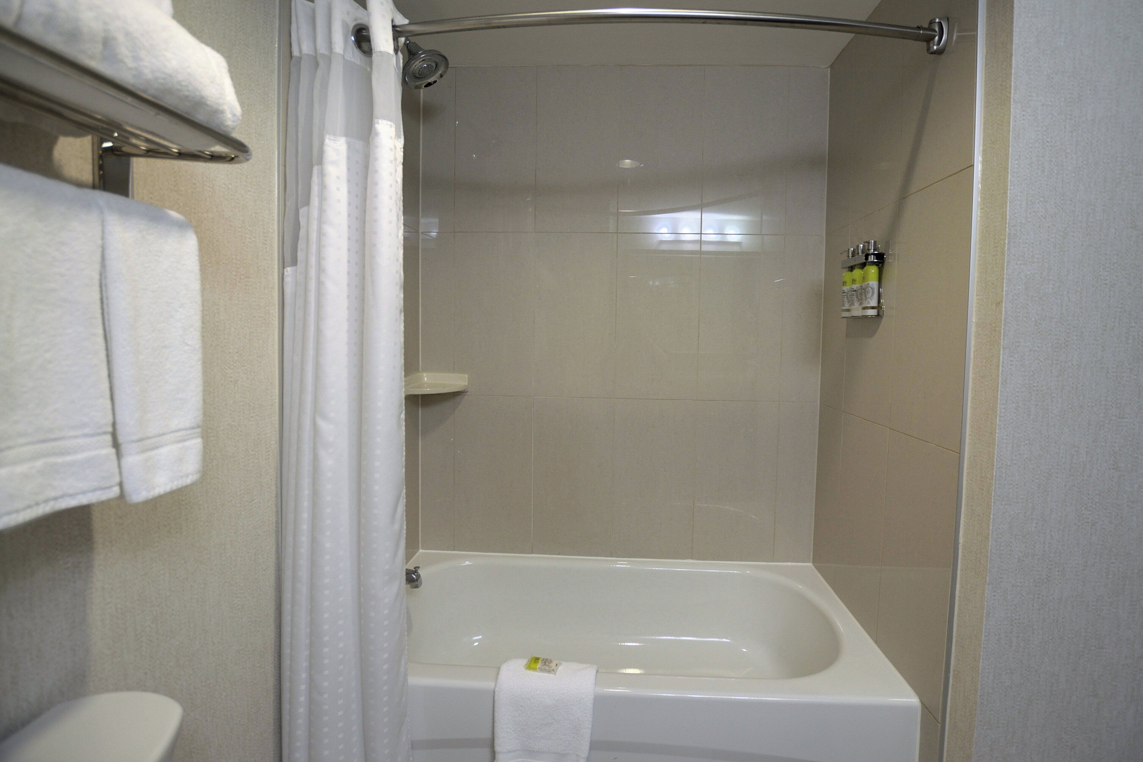 Un baño con bañera, cortina de ducha y toallero.