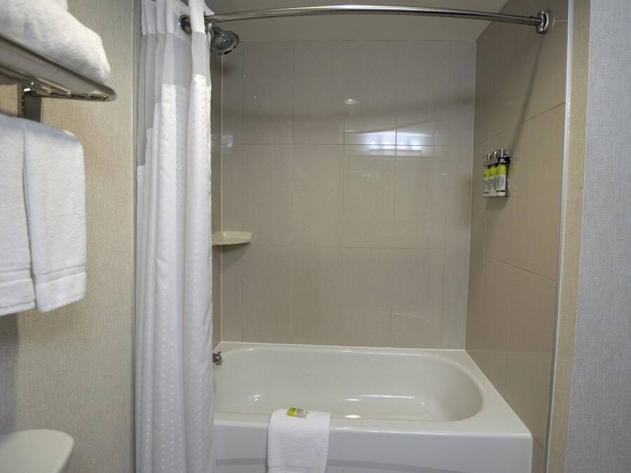 Un baño con bañera, cortina de ducha y toallero.