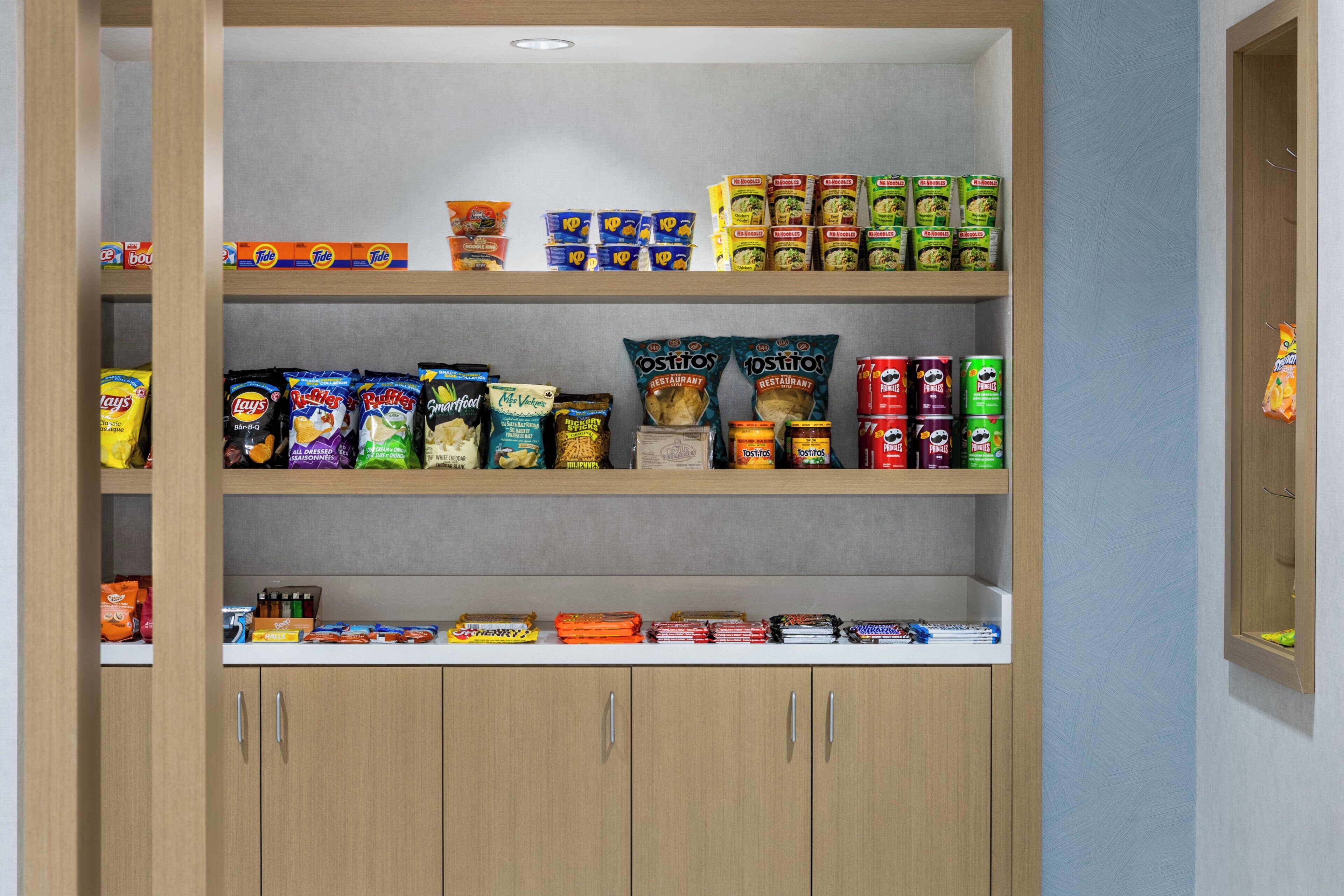 Eine Speisekammer mit verschiedenen Lebensmitteln, darunter Chips, Snacks und Konserven.