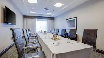 Conference room with a long table, comfortable chairs, and a flat-screen TV.
