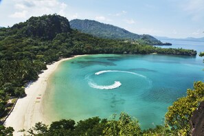 A beach with clear turquoise waters, a sandy shore, and lush greenery. - Dakak Park & Beach Resort (Dapitan)