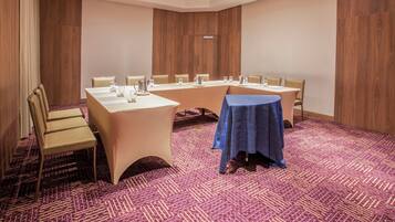 A conference room with a long table, chairs, and a smaller table covered with a blue cloth.
