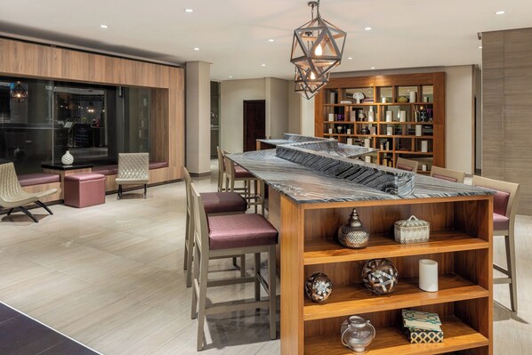 Un comedor moderno con una mesa y sillas de madera, una estantería empotrada y un colgador de luz decorativo.