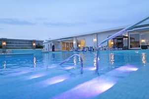 Una piscina al aire libre, sombrillas, sillones reclinables de piscina