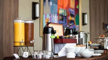 Montaje de un bufé de desayuno con dispensadores de jugo, máquinas de café y una gran variedad de alimentos.