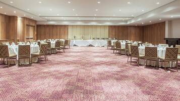 A conference room with rows of tables and chairs, a patterned carpet, and wooden paneling on the walls.