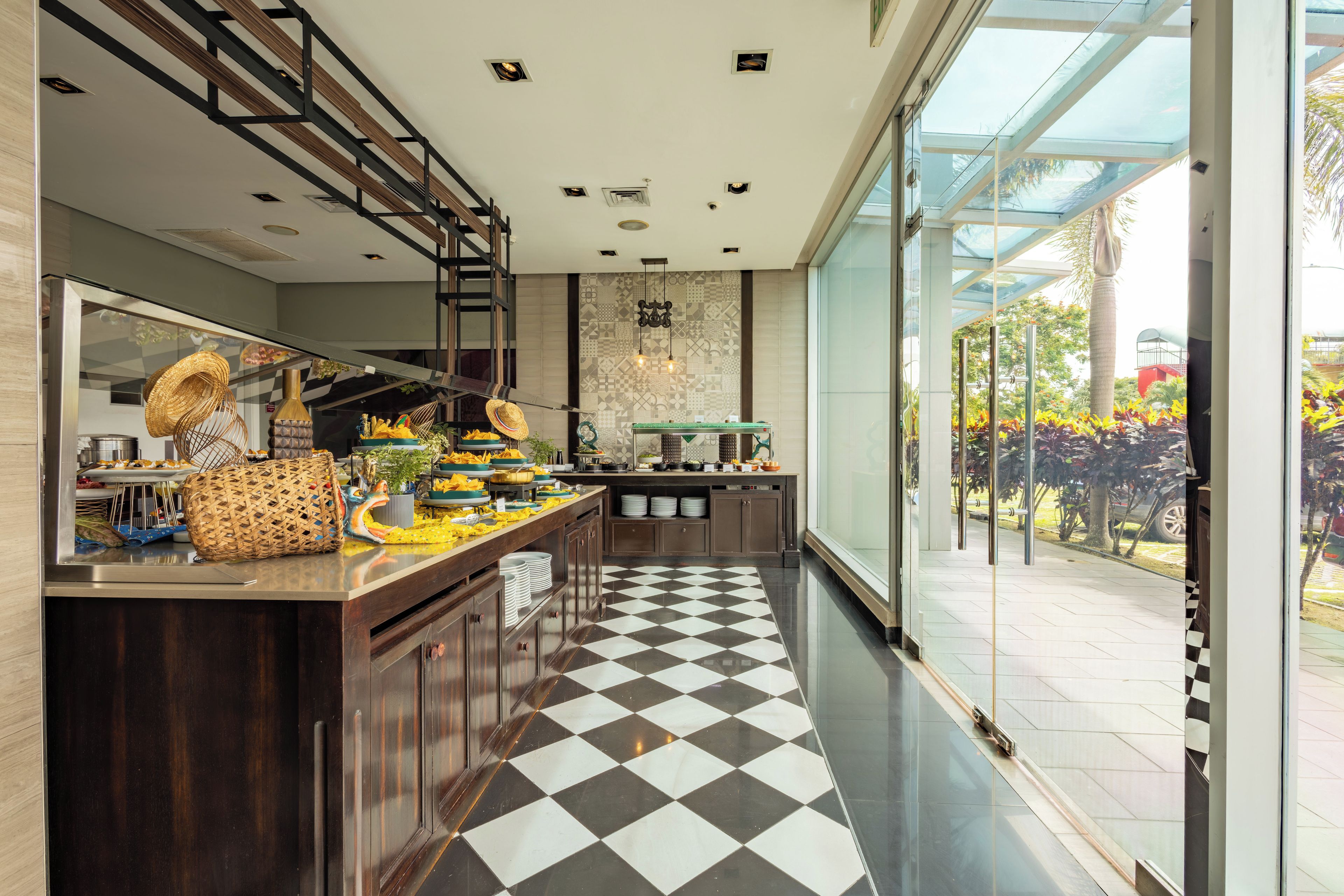 A modern kitchen with a checkered floor, wooden cabinets, and a glass enclosure leading to an outdoor area.