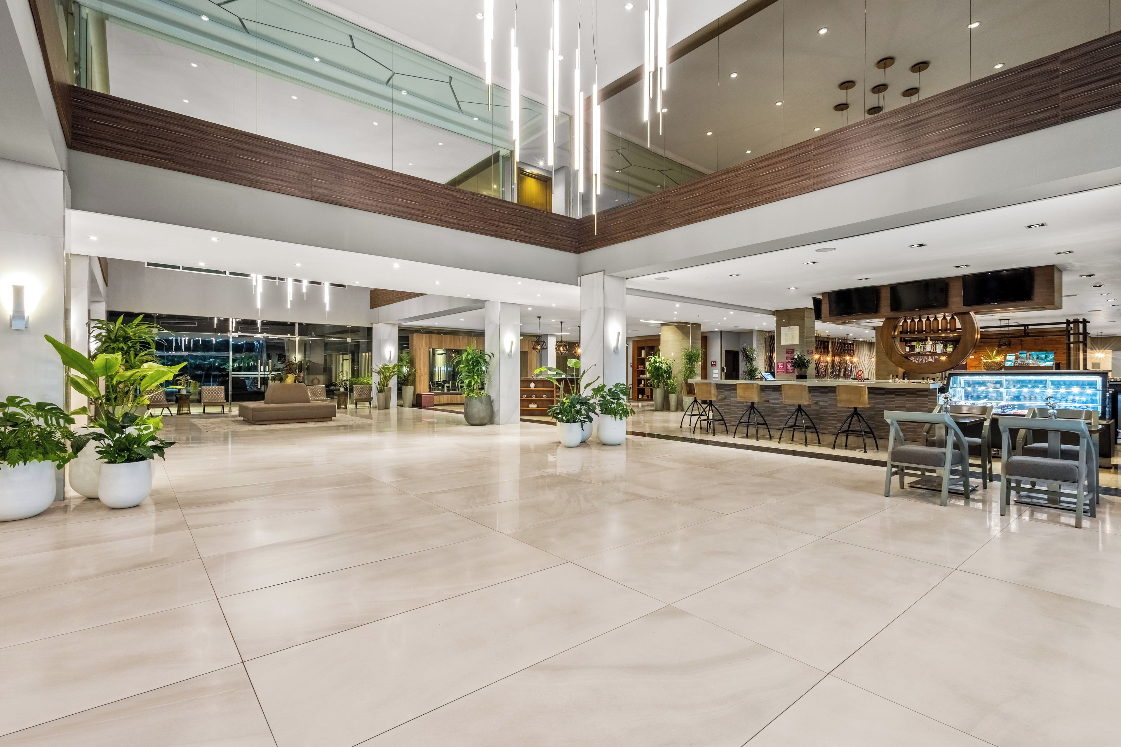 A spacious lobby with a coffee bar, seating area, and potted plants.