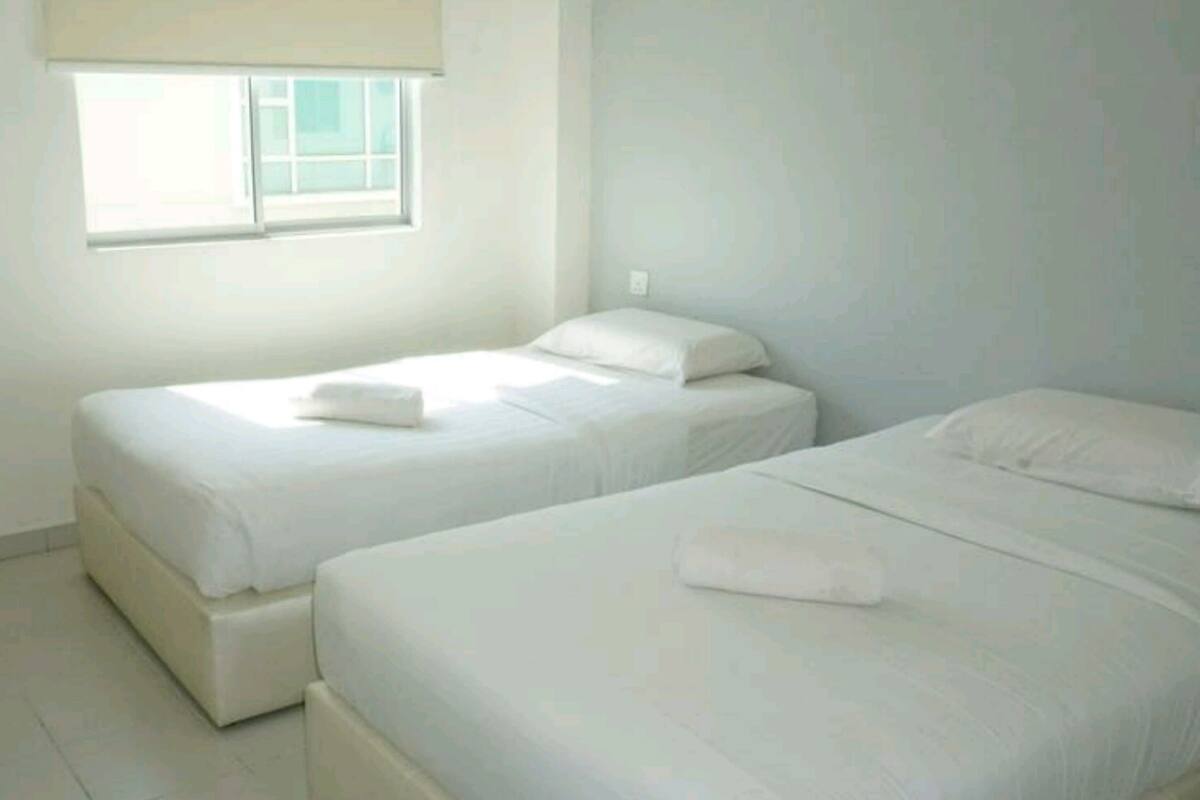 Een kamer met twee bedden, een raam met een zonnescherm en een betegelde vloer.
