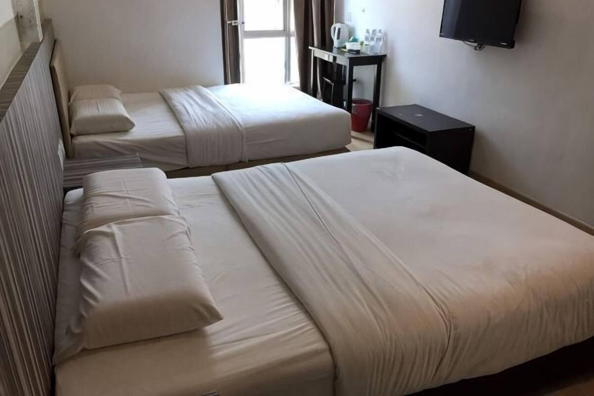 A hotel room with two beds, a TV, and a desk with a chair.