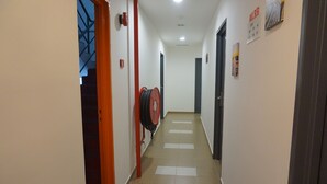 A hallway with a tiled floor, a red fire hose reel, and a door with a sign indicating room numbers. - Sun Inns Hotel Laksamana (Malacca City)