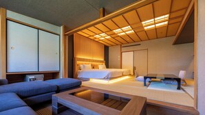 A modern hotel room with a sofa, a bed, a wooden coffee table, and a traditional Japanese sliding door. - Hotel Kajikaso (Hakone)