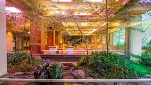 A modern indoor garden with seating areas, a water feature, and bamboo plants. - Hotel Kajikaso (Hakone)