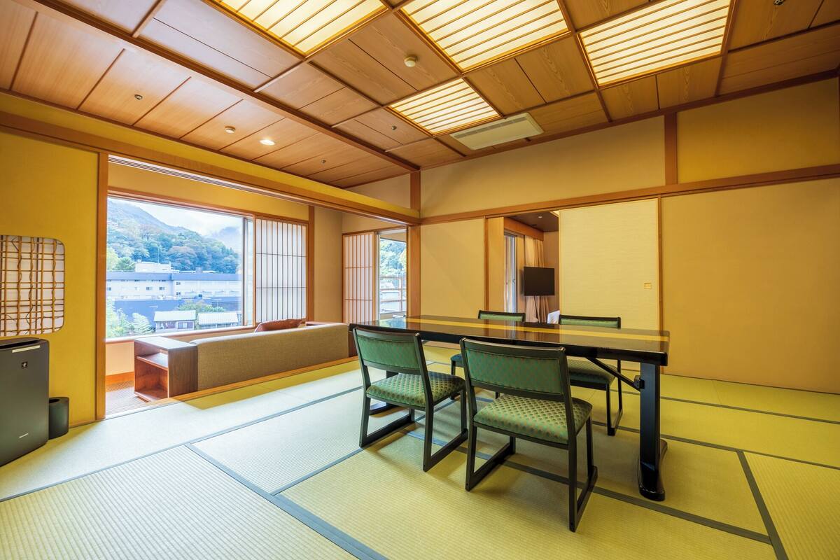 A traditional Japanese room with tatami flooring, a low table, and green chairs.