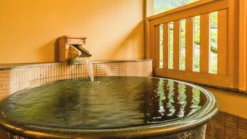 A hot tub with a wooden railing and a window with a view of greenery.
