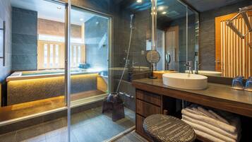 Un baño moderno con ducha envuelta en vidrio, un espejo grande y un mueble de tocador de madera.