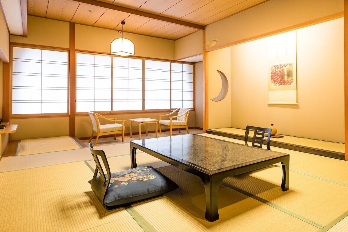 Um quarto japonês tradicional com piso de tatame, uma mesa baixa e painéis shoji.