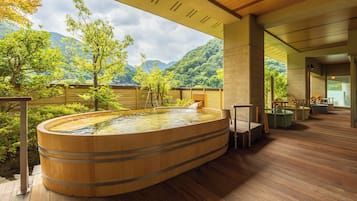 A wooden hot tub with a view of a mountainous landscape.