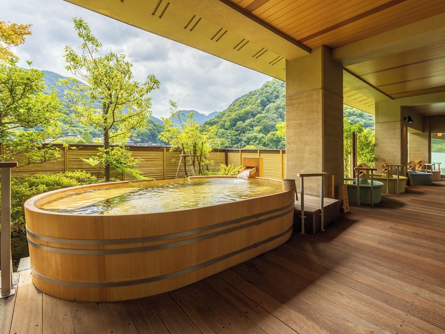 A wooden hot tub with a view of a mountainous landscape.