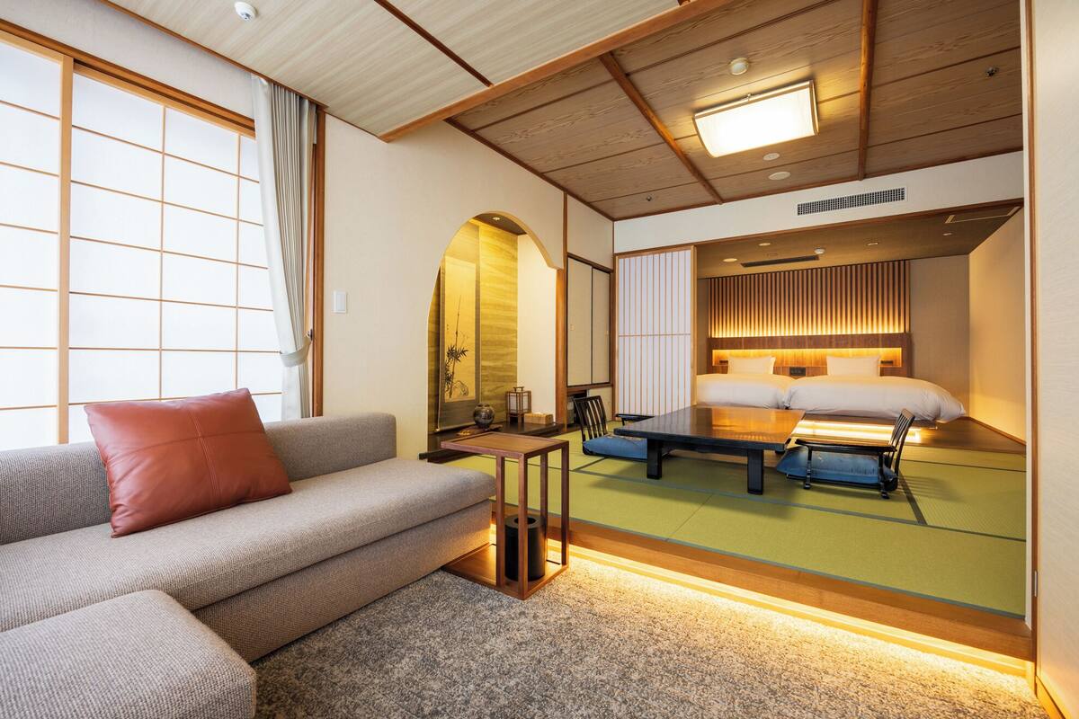 A hotel room with a sofa, a table, and a bed with a wooden headboard.