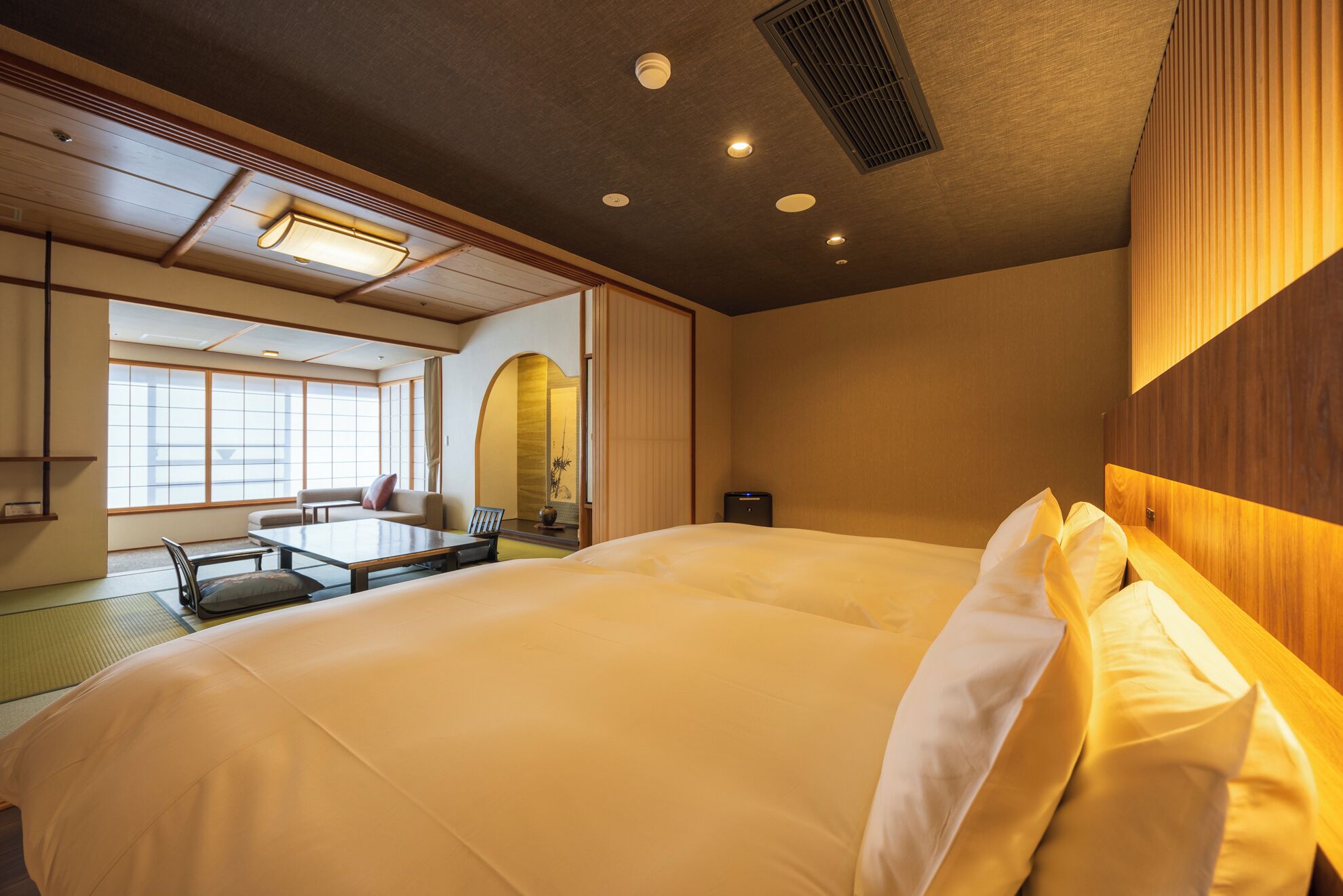 Habitación de hotel con una cama grande, un escritorio y una zona de estar con vistas a la ciudad.