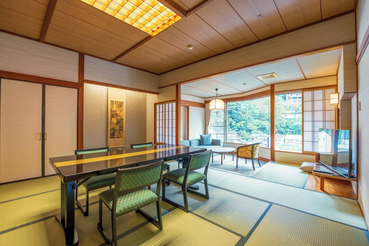 A traditional Japanese-style room with tatami flooring, a low table with chairs, and sliding doors.