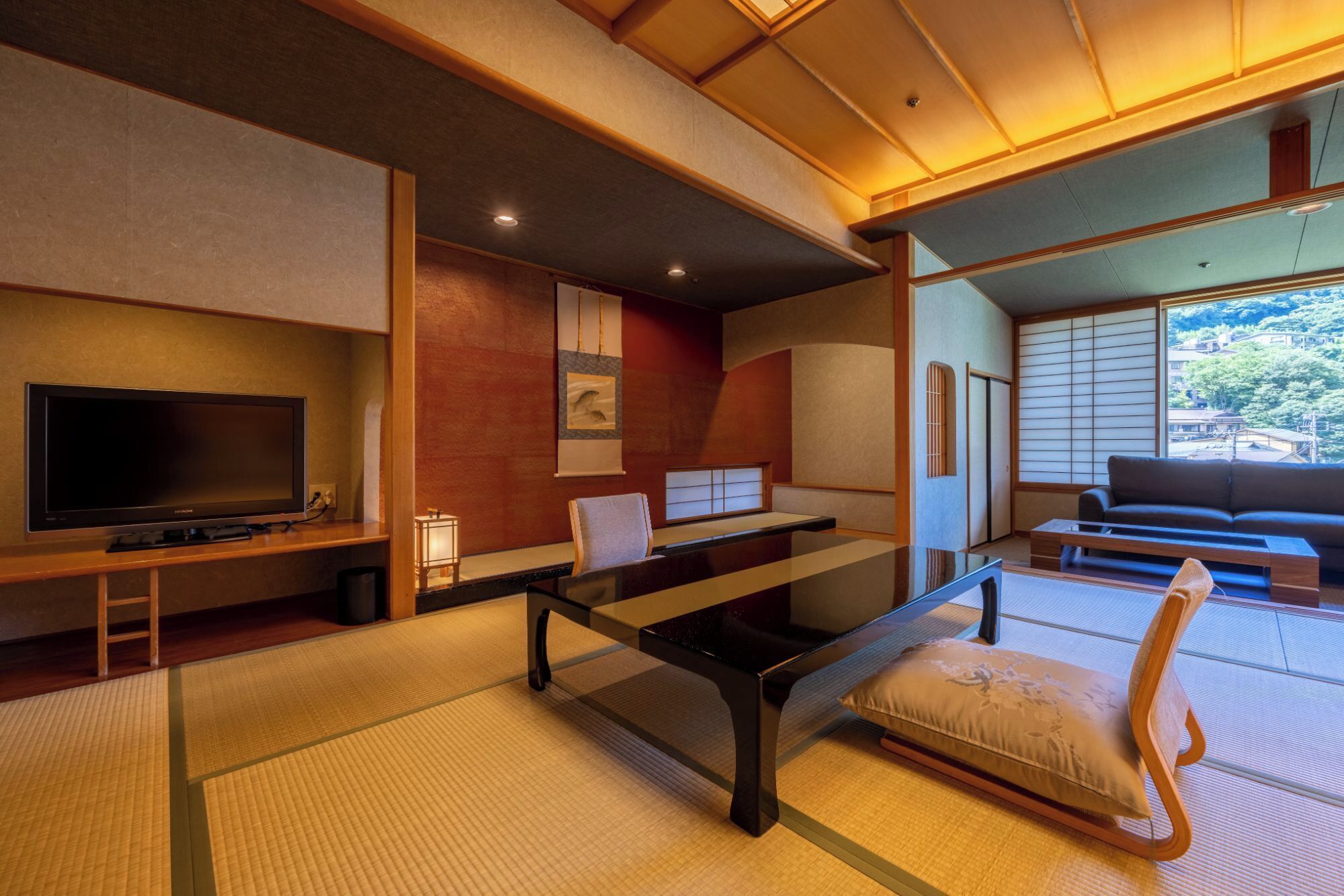 Un salon de style japonais traditionnel, avec un sol recouvert de tatamis, une table basse, un canapé et un téléviseur.