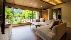 A modern living room with a large window, a sofa, a coffee table, and a TV. - Hotel Kajikaso (Hakone)