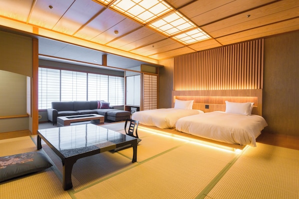 Una habitación de estilo japonés tradicional, con suelo de tatami, una mesa baja, un sofá y una cama con cabecera de madera.